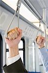 People holding handles on train