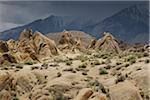 Rock formations of the Alabama Hills with storm clouds over the Sierra Nevada Mountains in the background in Eastern California, USA