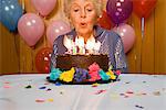 Senior woman blowing out candles on cake