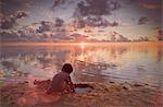 Boy playing in wet sand on tranquil sunset beach