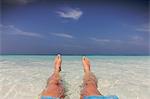 Personal perspective barefoot man relaxing, laying in tropical ocean surf