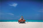 Woman relaxing, sunbathing, laying on lounge chair and using digital tablet on sunny tropical beach