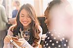 Female friends texting with cell phones in cafe