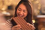 Woman with sweet tooth craving biting into large chocolate bar