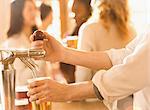 Close up bartender pouring beer at beer tap in bar