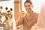 Portrait smiling man toasting beer glass at bar