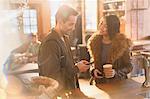 Couple with cell phone and coffee at counter in cafe