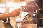 Close up barista wiping down espresso machine milk frother with rag in cafe