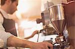 Barista using espresso machine grinder in cafe