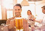 Portrait smiling man toasting beer stein in bar