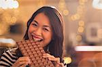 Portrait Chinese woman with sweet tooth craving biting into large chocolate bar