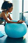 Young woman exercising in gym, using inflatable exercise ball