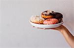 Female hand holding plate of doughnut holes