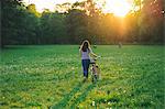 Woman walking bicycle on grass