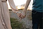 Couple holding hands, outdoors, mid section, close-up