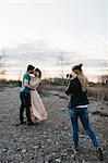 Photographer photographing couple, couple kissing in rural setting