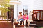 Mother and adult daughter sitting on porch