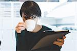 Woman in cafe looking at digital tablet and drinking coffee