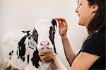 Female organic farmer petting calf at dairy farm