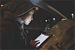 Woman in car front seat using digital tablet touchscreen in city at night