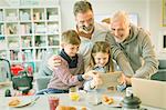 Male gay parents and children video messaging with digital tablet in morning kitchen