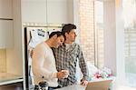 Affectionate male gay couple with coffee in kitchen