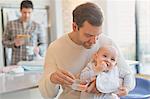 Father feeding carrots to baby son