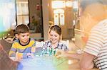 Father and children playing board game at table