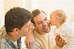 Affectionate baby son kissing male gay parents