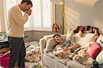 Male gay parents resting with baby son on sofa