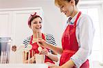 Smiling female caterers baking, making cupcake pops in kitchen