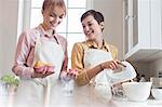 Smiling female caterers baking muffins in kitchen