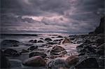 Large rocks on stormy, overcast nighttime beach, Bisserup, Denmark