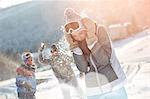 Playful skier friends enjoying snowball fight in snowy field