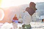 Playful couple enjoying snowball fight in sunny snowy field