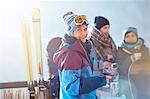 Portrait smiling female skier drinking cocktail on balcony with friends apres-ski