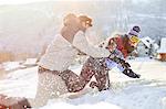 Playful couple enjoying snowball fight in snowy field