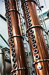 Tall copper distillery chambers in a brewery, brewing storage tanks in copper and steel.