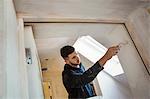 A builder, painter holding a paint brush, painting a door frame.