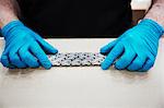 Close up of worker wearing blue latex gloves, holding a bicycle chain.