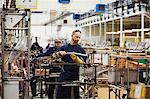 A man wearing one protective glove with sunglasses on his head,  skilled factory worker working on bicycle parts in a factory.