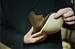 Close up of worker in a shoemaker's workshop, attaching a sole to a leather boot.