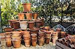 A large stack of terracotta pots in a garden.