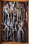 Overhead view of a box of old rusty worn metal shears, tin snips and pliers in a workshop.