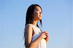 Young Japanese woman in a white dress at a cliff over the sea at sunrise, Chiba, Japan