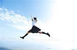 Young Japanese woman in a high school uniform jumping by the sea, Chiba, Japan