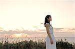 Young Japanese woman in a white dress at a cliff over the sea at sunrise, Chiba, Japan