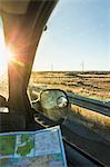 Wing mirror view of man with map on the road in sunlight, Arizona, USA