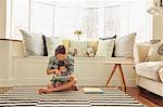 Baby girl sitting on mother's lap reading book in living room