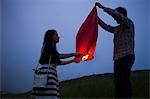 Couple in field at dusk, releasing sky lantern